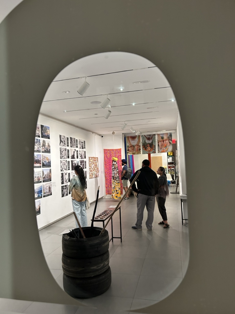 View through an arched opening into the gallery at the 2024 New York City exhibit, with visitors among the artworks